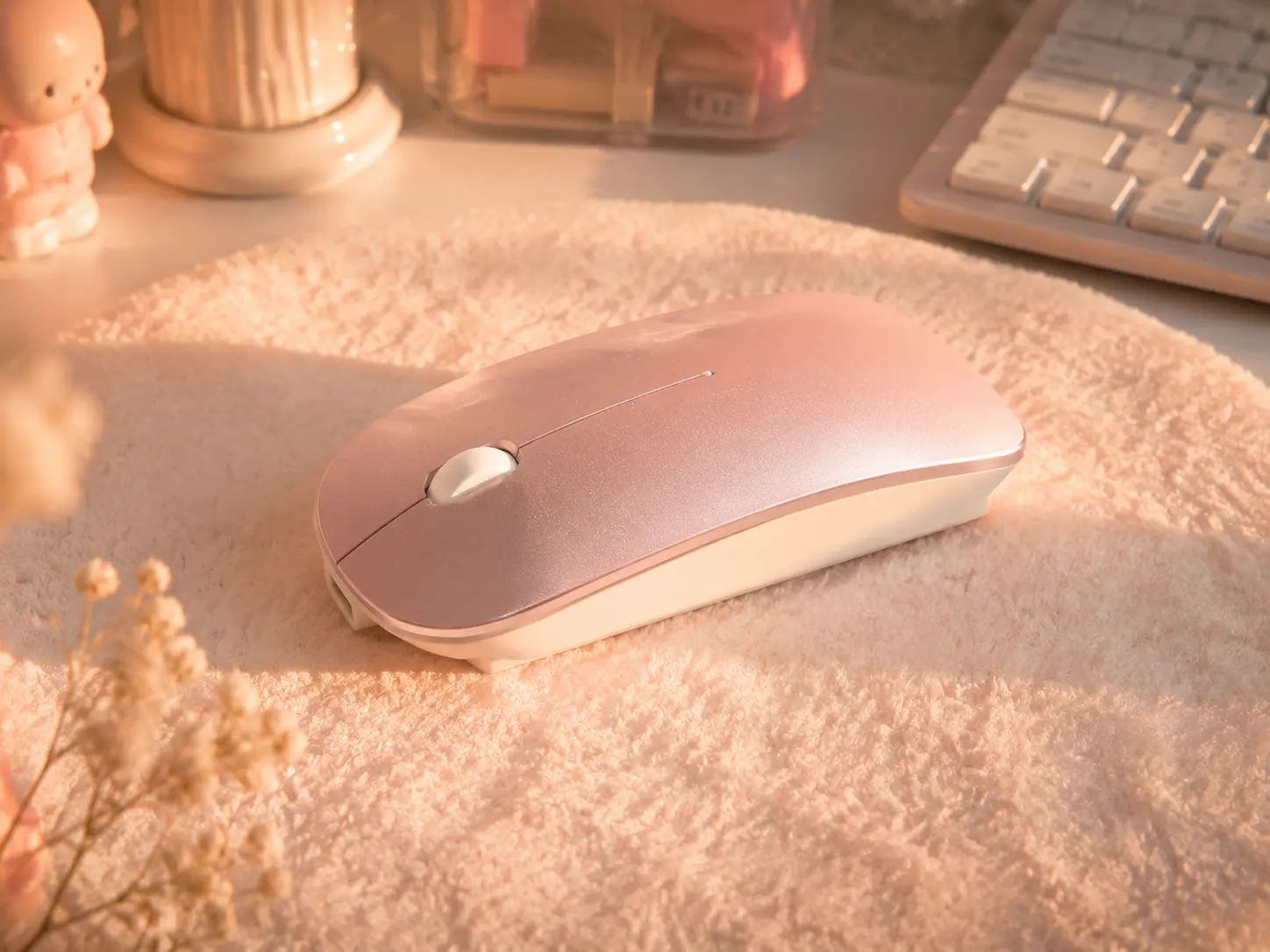 Photorealistic close-up of a soft pastel pink wireless mouse resting on a fluffy desk mat