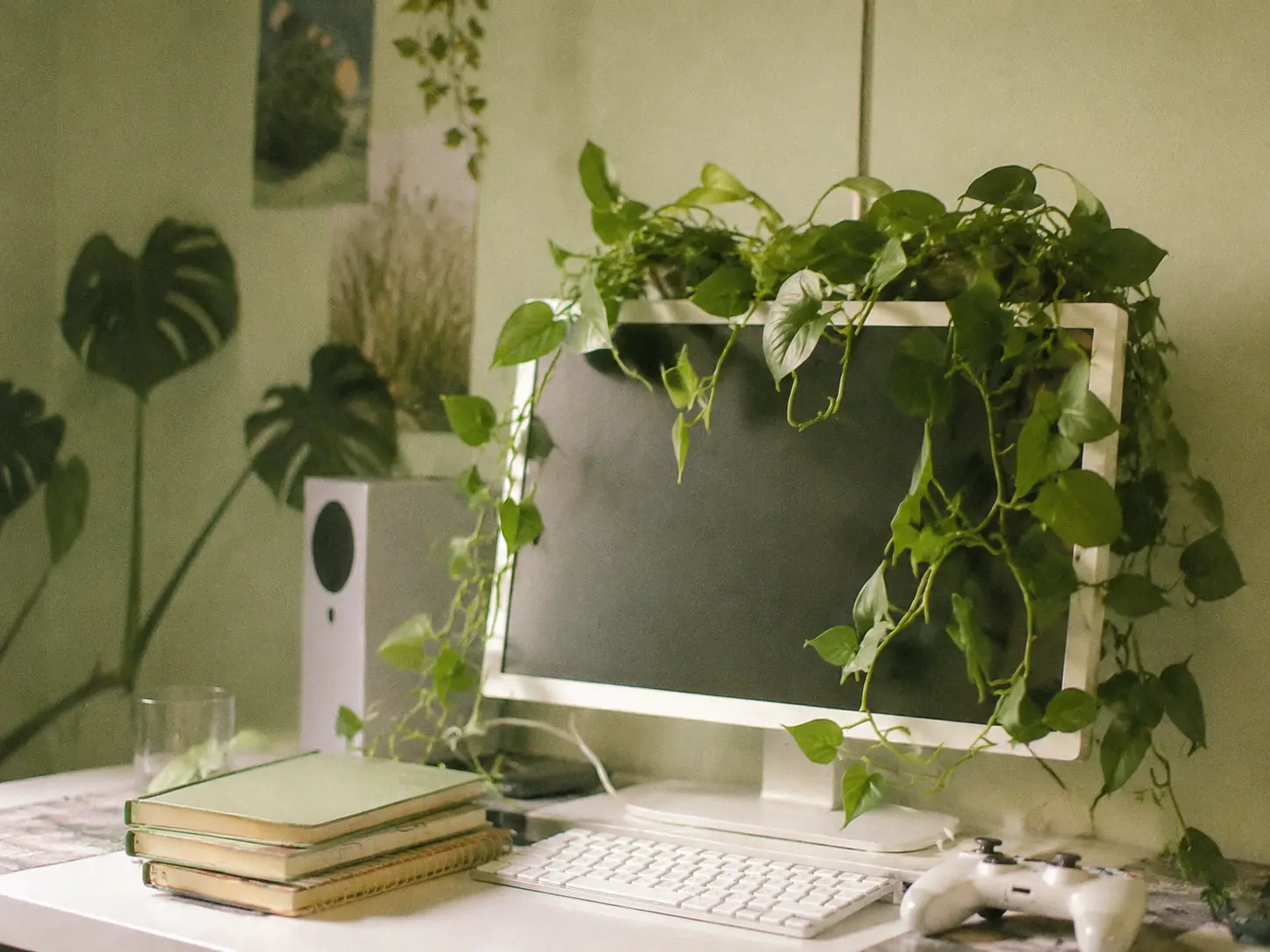 Faux trailing pothos plants draped over a white PC monitor in a cozy room