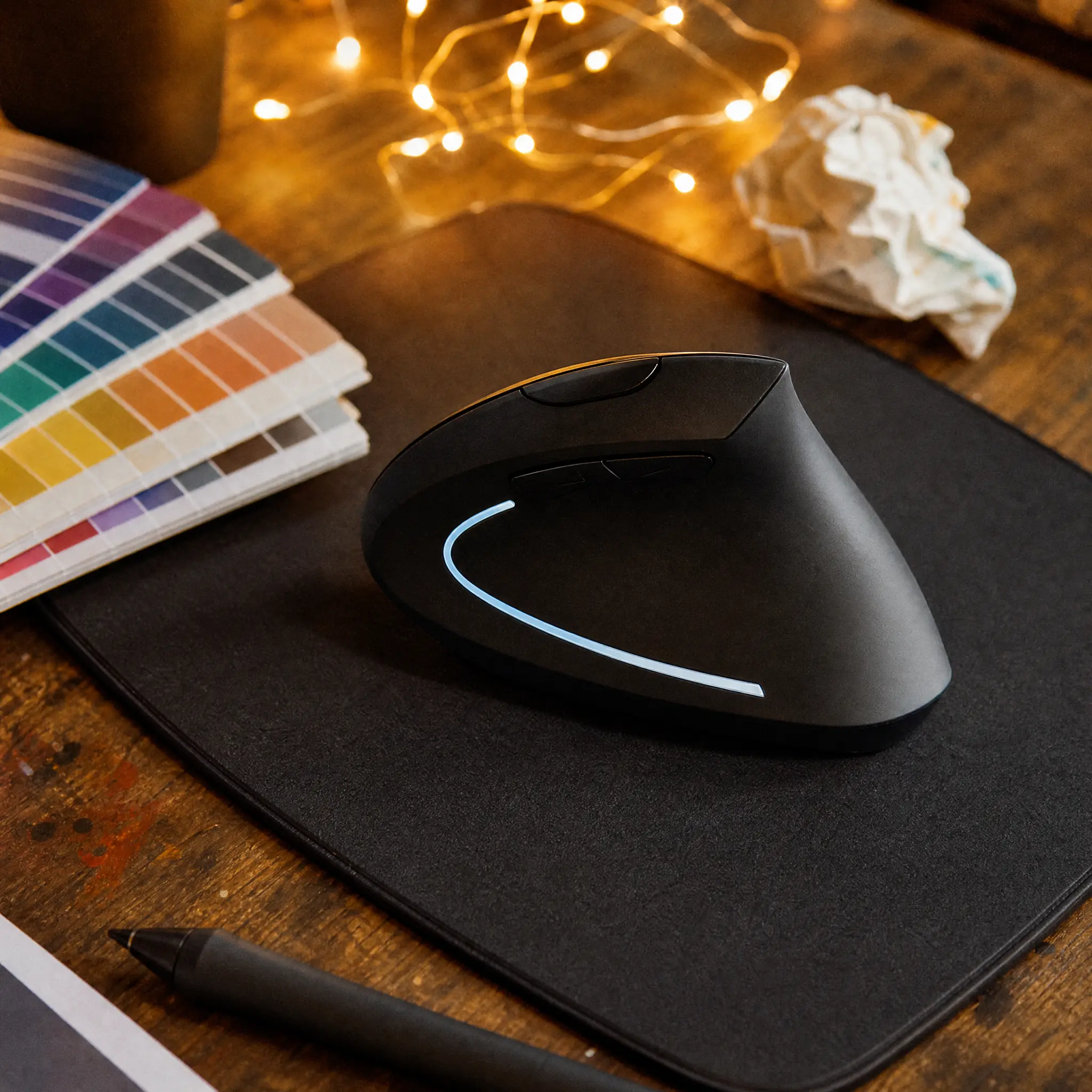 Vertical ergonomic mouse on a wooden desk with coffee and sticky notes