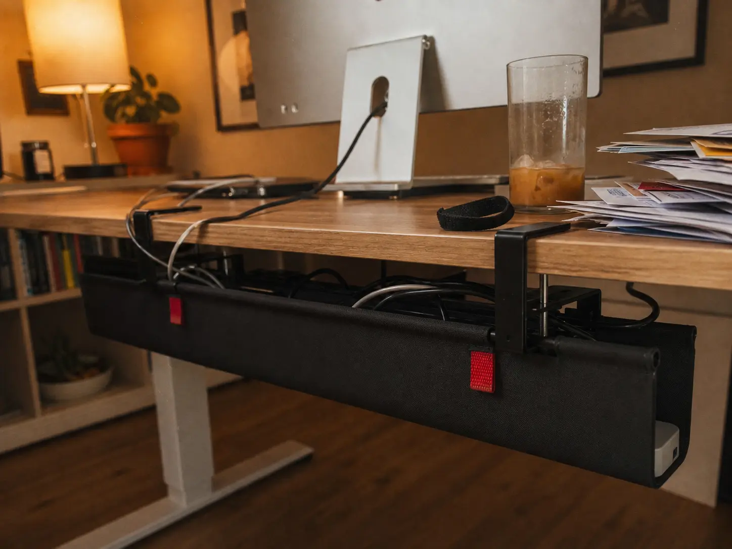 Sleek clamp-on cable management tray under a wooden standing desk