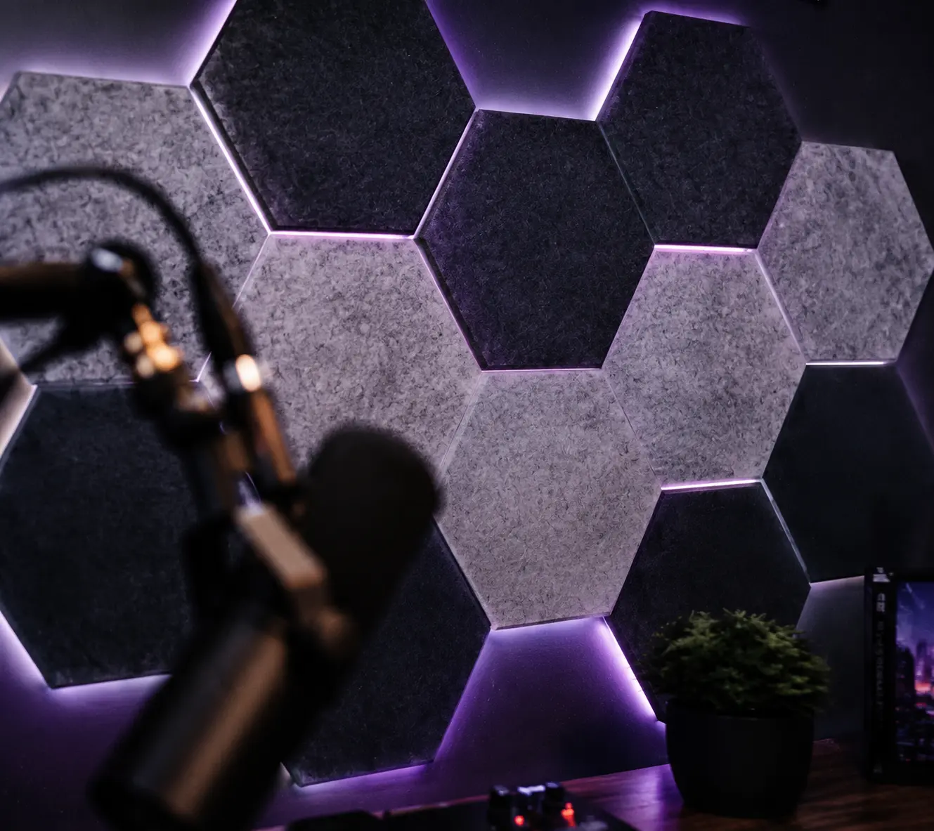 Dark grey hexagon acoustic felt panels arranged creatively on a wall above a microphone