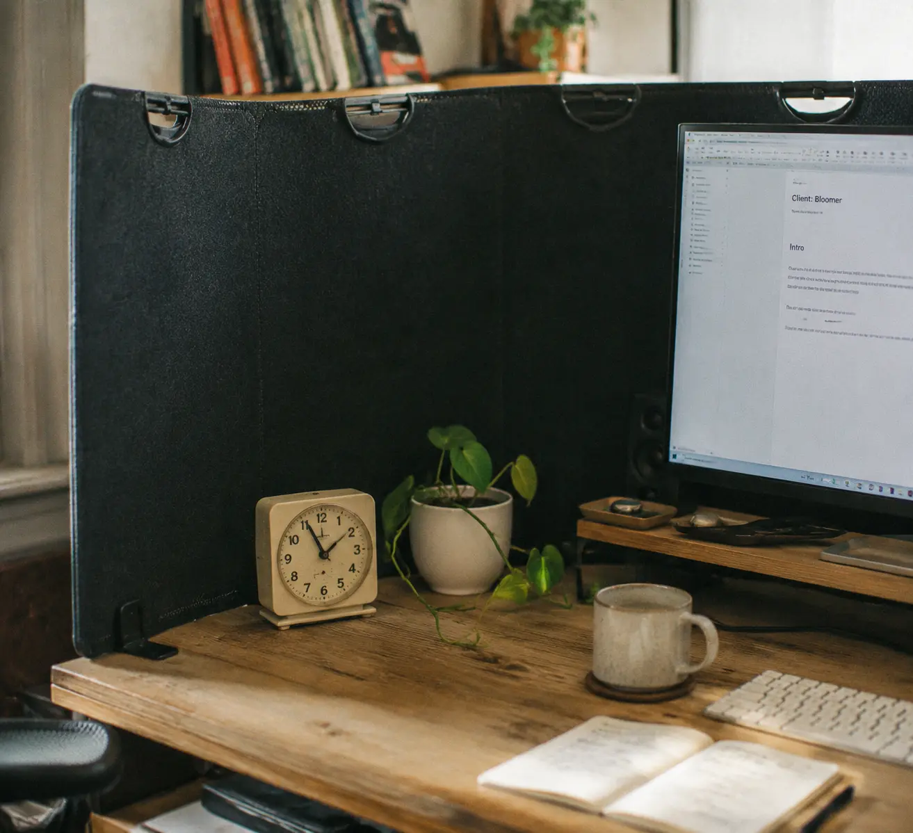 Thick grey acoustic privacy panel clamped to the edge of a wooden desk