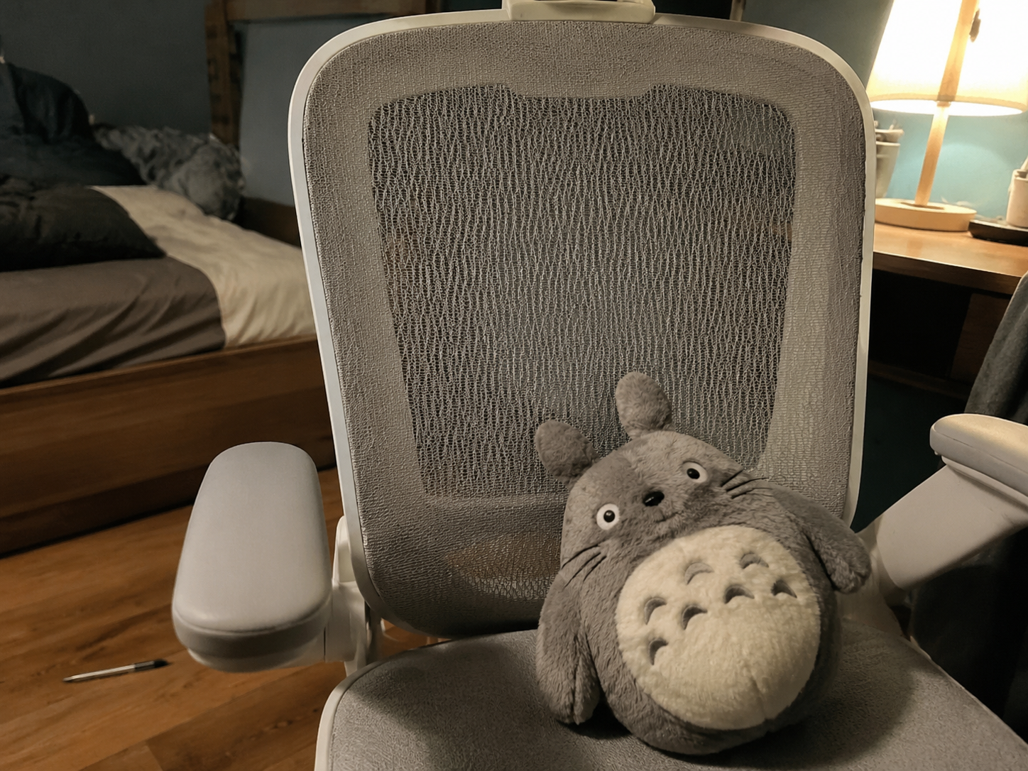 White frame minimalist ergonomic mesh chair in a cozy bedroom with ambient lighting