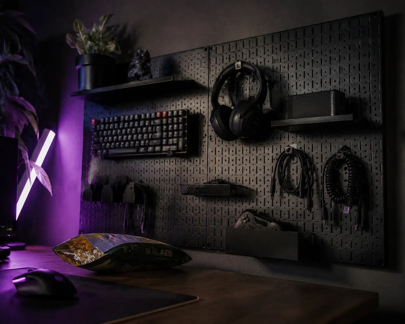 Black metal pegboard holding heavy gaming headset and cables on a dark grey wall