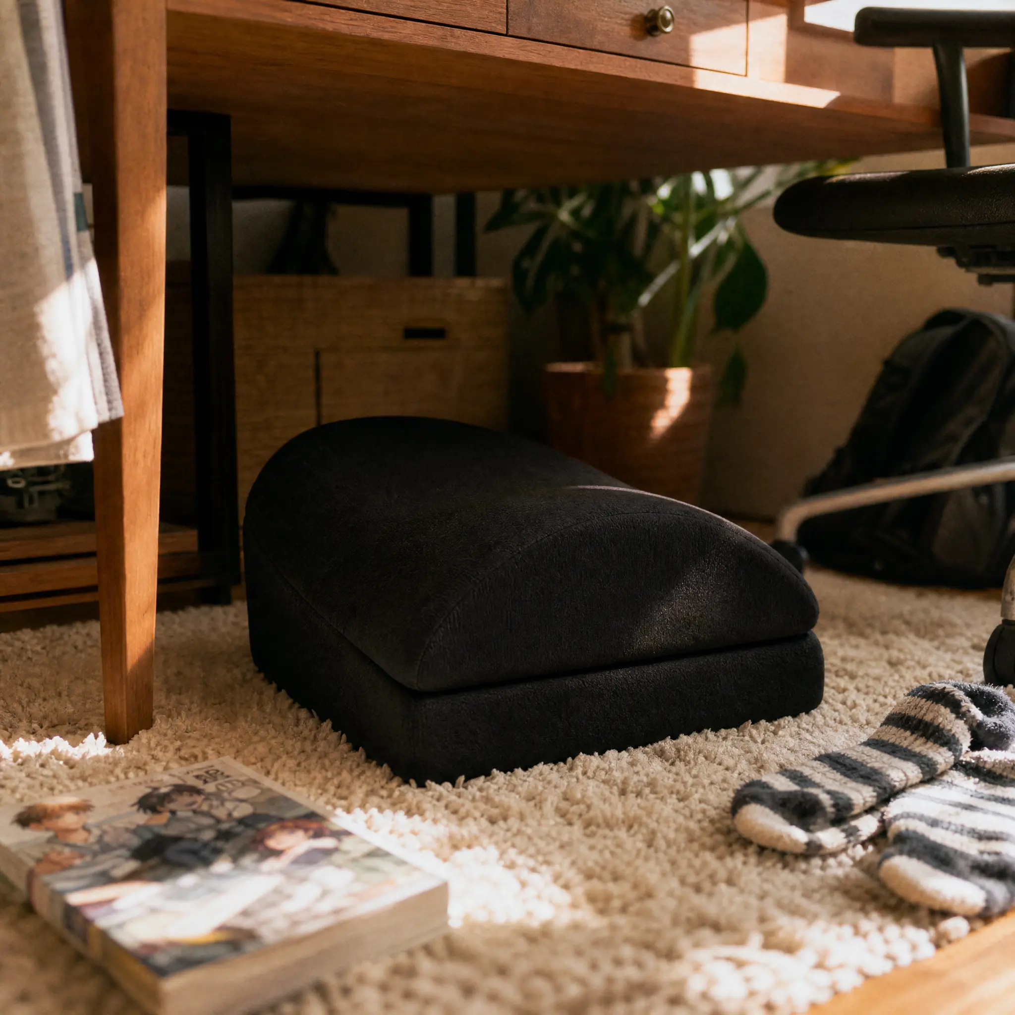 Soft memory foam teardrop footrest on a fluffy rug under a wooden desk