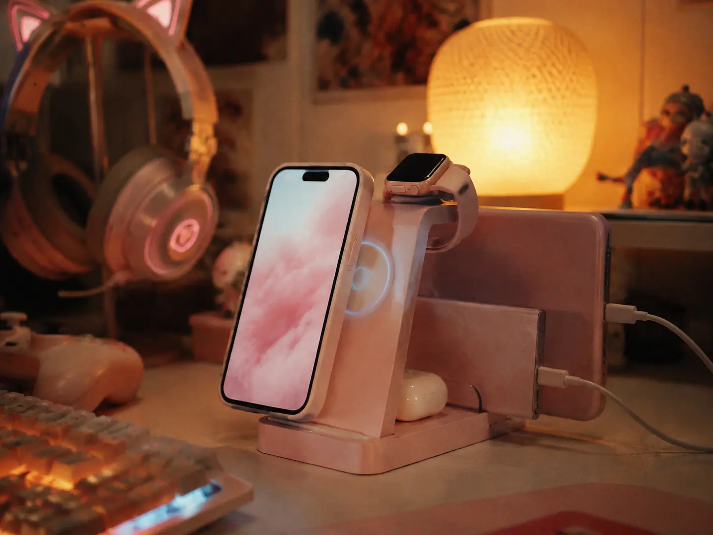 Cute pastel pink wireless charging pad on a cozy lit gaming desk