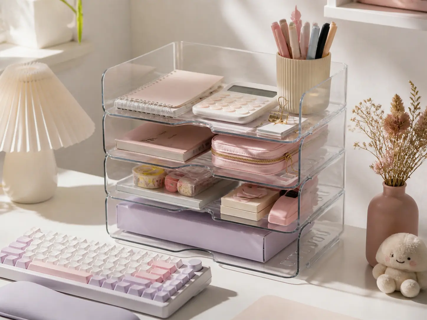 Clear acrylic stackable desk organizer holding pastel stationery on a white desk
