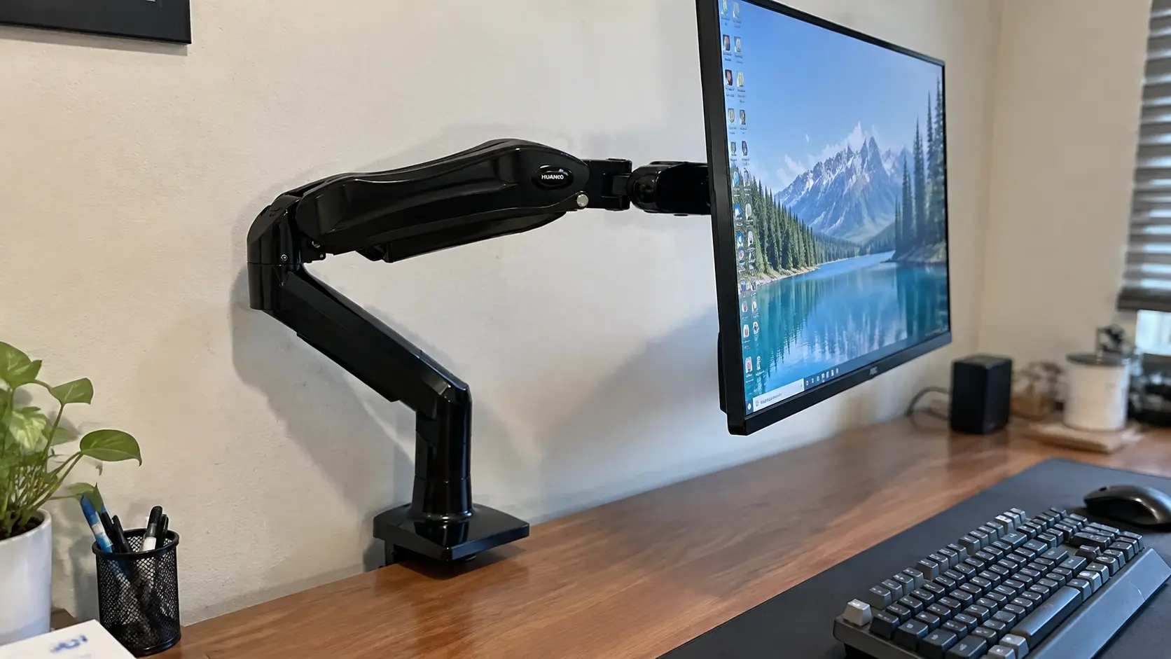 HUANUO gas spring monitor mount attached to a wooden desk